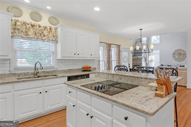 kitchen with light wood-type flooring, tasteful backsplash, black electric cooktop, and a sink