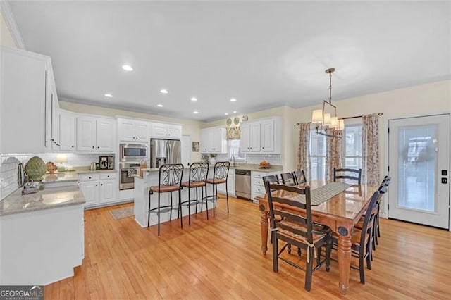 dining space featuring light hardwood / wood-style floors, an inviting chandelier, and sink