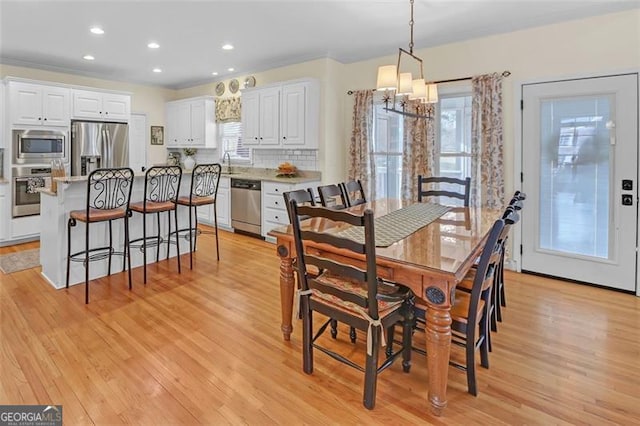 dining room featuring a chandelier, light hardwood / wood-style floors, ornamental molding, and sink