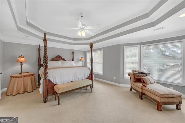 carpeted bedroom featuring ornamental molding, a tray ceiling, visible vents, and baseboards