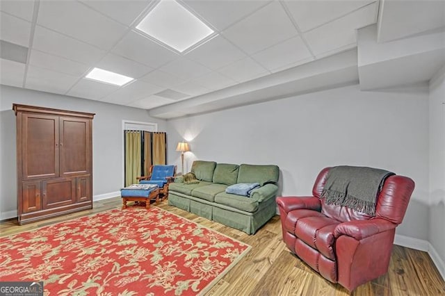 living room with a paneled ceiling, baseboards, and wood finished floors