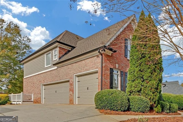 view of side of property featuring a garage, concrete driveway, and brick siding