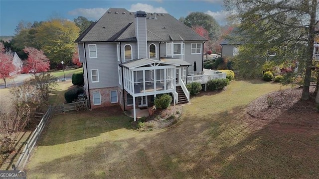 back of house featuring stairway, a sunroom, a yard, and a chimney