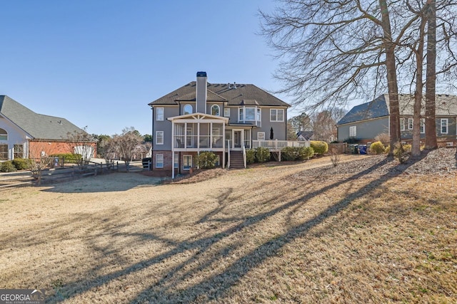 back of property with stairway, a sunroom, and a chimney