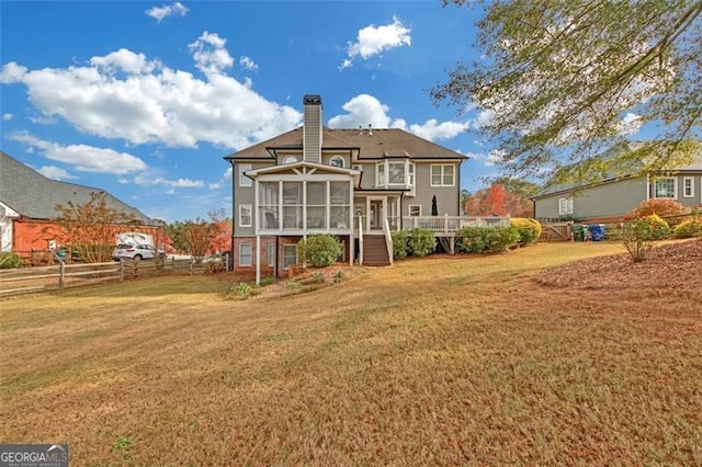 back of property with a sunroom, a chimney, fence, and a yard