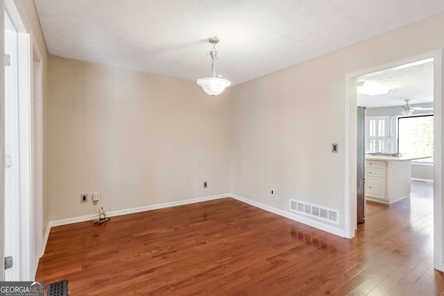 empty room with ceiling fan, hardwood / wood-style floors, and a textured ceiling