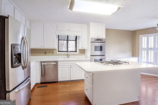 kitchen featuring sink, a center island, stainless steel appliances, light hardwood / wood-style flooring, and white cabinets