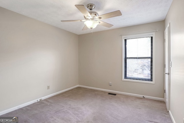 carpeted spare room featuring ceiling fan and a textured ceiling