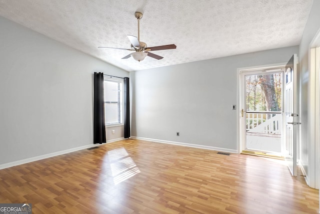 spare room featuring lofted ceiling, light hardwood / wood-style flooring, ceiling fan, and a textured ceiling