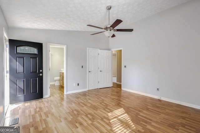 interior space with ensuite bath, ceiling fan, light hardwood / wood-style flooring, high vaulted ceiling, and a textured ceiling