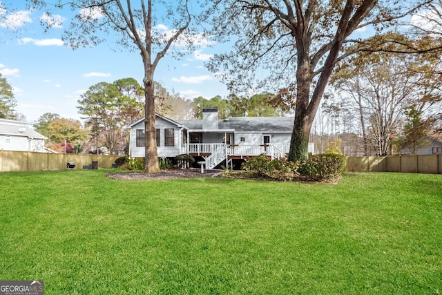 rear view of house with a lawn and a wooden deck