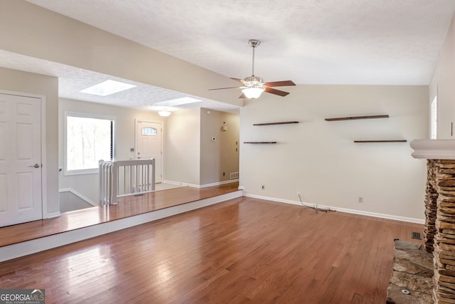 unfurnished living room featuring wood-type flooring, a textured ceiling, and lofted ceiling with skylight