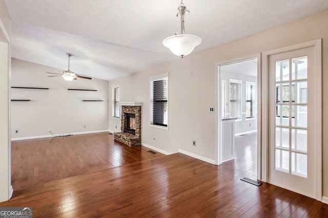 unfurnished living room with a textured ceiling, ceiling fan, dark wood-type flooring, and vaulted ceiling