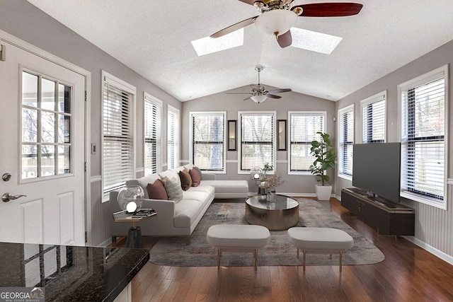 living room featuring a textured ceiling, ceiling fan, dark wood-type flooring, and vaulted ceiling with skylight