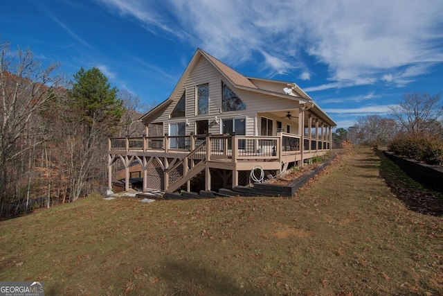 back of property featuring ceiling fan, a lawn, and a wooden deck