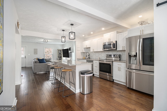 kitchen with a center island, white cabinets, dark hardwood / wood-style floors, decorative light fixtures, and stainless steel appliances