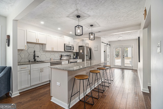 kitchen featuring light stone countertops, appliances with stainless steel finishes, sink, a barn door, and dark hardwood / wood-style floors