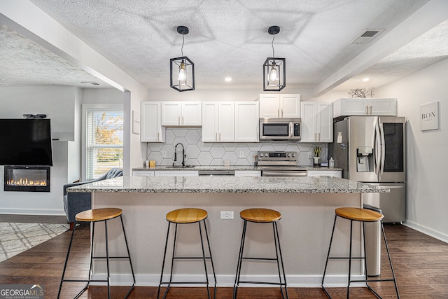 kitchen with white cabinets, dark wood-type flooring, appliances with stainless steel finishes, and a textured ceiling