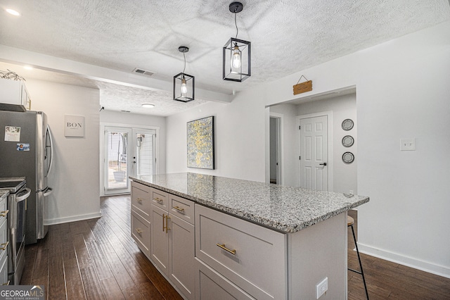 kitchen with a kitchen breakfast bar, light stone counters, a textured ceiling, dark wood-type flooring, and hanging light fixtures