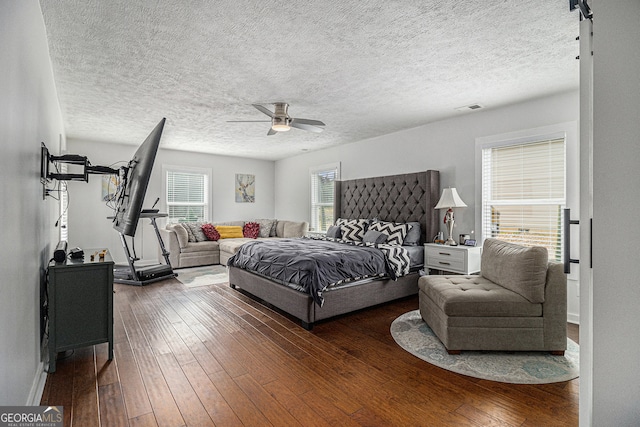 bedroom with ceiling fan, dark hardwood / wood-style flooring, and a textured ceiling