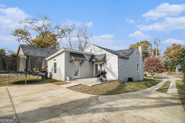 back of property featuring a trampoline and a patio area