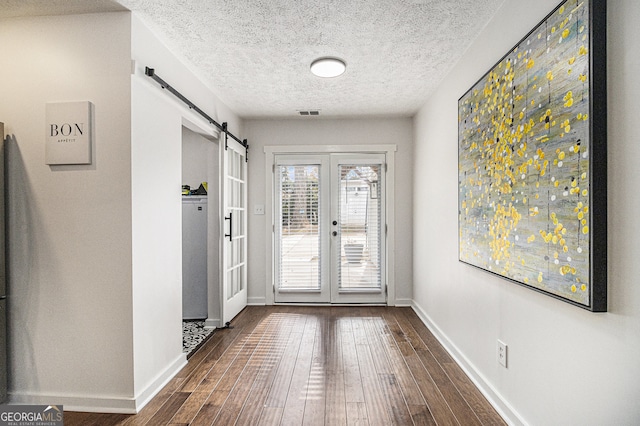 doorway featuring french doors, a barn door, dark hardwood / wood-style floors, and a textured ceiling