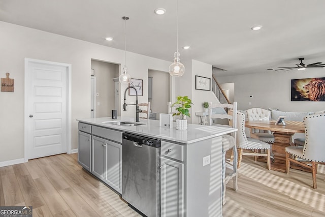 kitchen with dishwasher, a kitchen island with sink, sink, gray cabinets, and decorative light fixtures