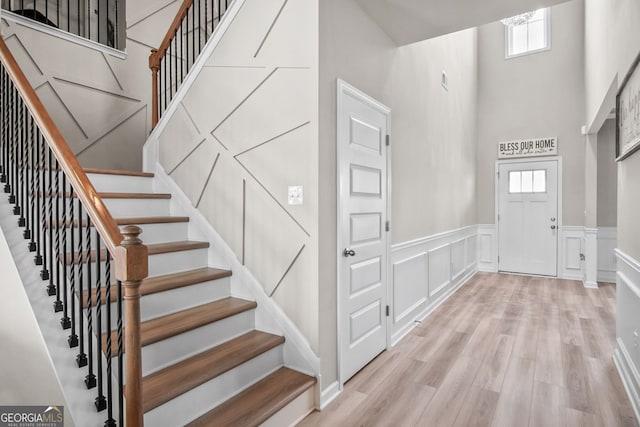 entryway featuring light wood-type flooring and a towering ceiling