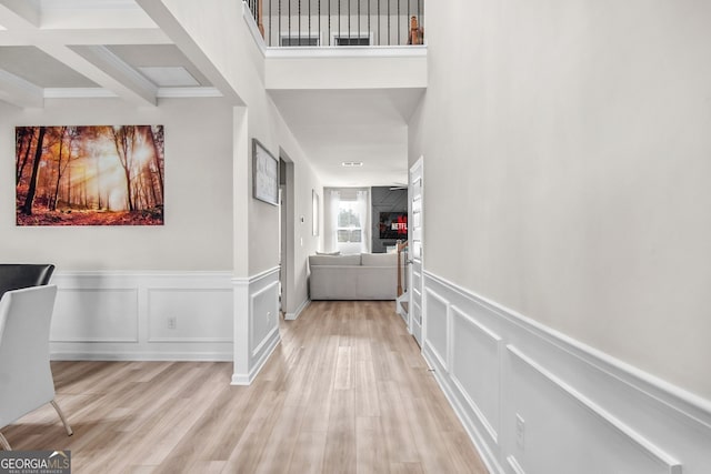 hall with light hardwood / wood-style flooring and beamed ceiling