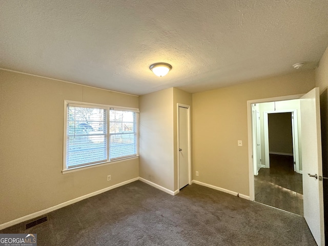 unfurnished bedroom featuring dark carpet, a textured ceiling, and a closet