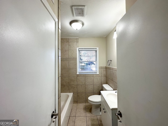 bathroom with vanity, tile patterned floors, toilet, tile walls, and a textured ceiling