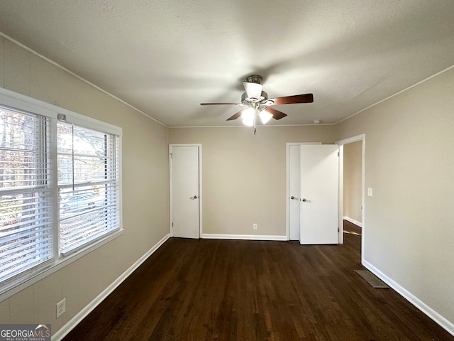 unfurnished bedroom featuring a textured ceiling, crown molding, ceiling fan, and dark wood-type flooring