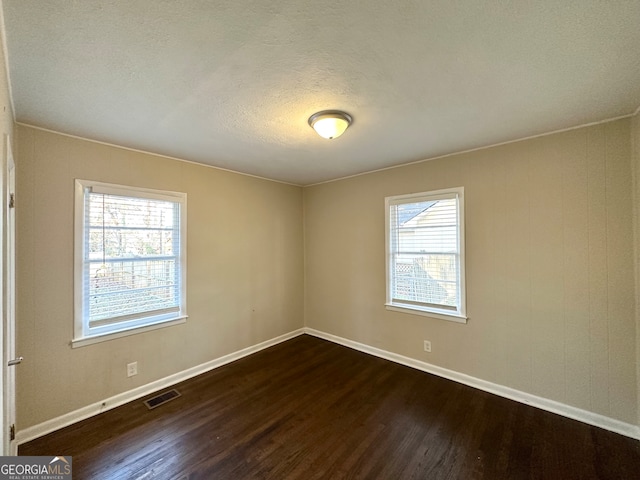 empty room featuring crown molding, dark hardwood / wood-style flooring, and a textured ceiling