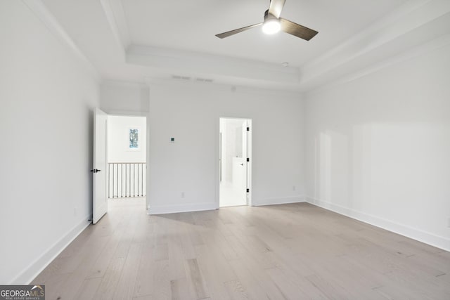 spare room with ceiling fan, light wood-type flooring, ornamental molding, and a tray ceiling