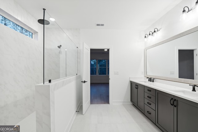 bathroom with tile patterned flooring, vanity, and tiled shower