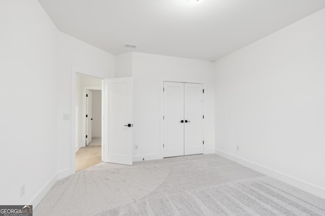 unfurnished bedroom with light carpet and a closet