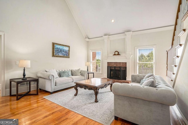 living room featuring a fireplace, light hardwood / wood-style floors, high vaulted ceiling, and plenty of natural light