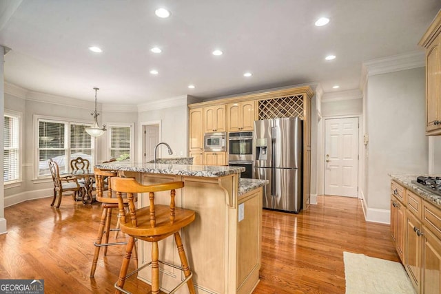 kitchen featuring appliances with stainless steel finishes, a kitchen island with sink, crown molding, pendant lighting, and light hardwood / wood-style floors