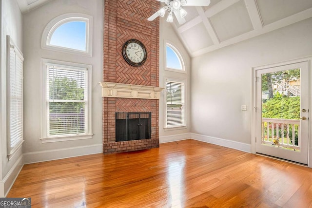 unfurnished living room with ceiling fan, light wood-type flooring, a wealth of natural light, and a brick fireplace