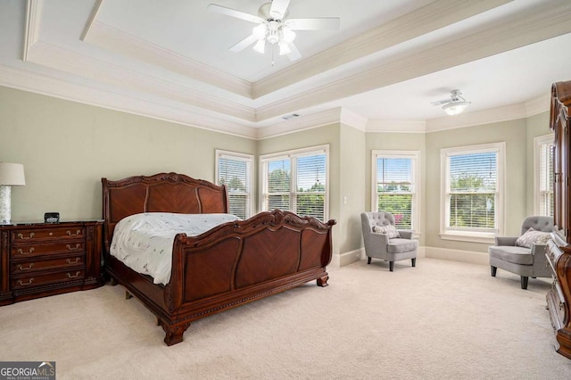 bedroom featuring a tray ceiling, multiple windows, ceiling fan, and light colored carpet