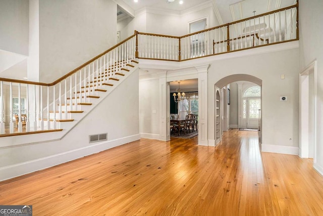 entryway featuring a chandelier, crown molding, a towering ceiling, and wood-type flooring