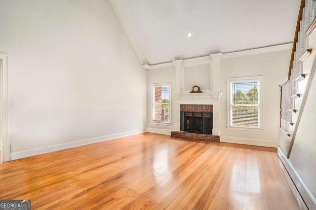 unfurnished living room with light hardwood / wood-style floors, ornamental molding, a fireplace, and a wealth of natural light