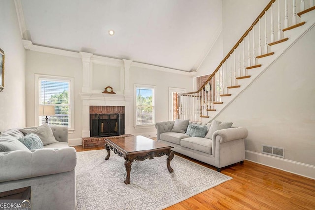 living room featuring hardwood / wood-style floors, a brick fireplace, and crown molding