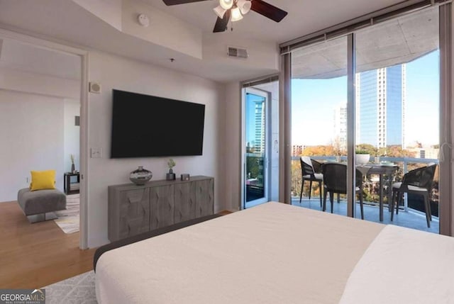 bedroom featuring expansive windows, ceiling fan, wood-type flooring, and access to outside