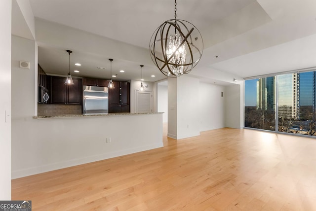 unfurnished living room with a notable chandelier and light hardwood / wood-style floors