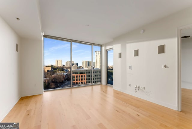 spare room with expansive windows and light wood-type flooring