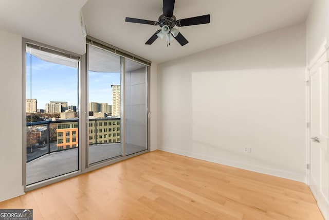 spare room with hardwood / wood-style flooring, ceiling fan, and floor to ceiling windows