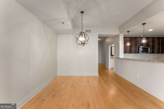 unfurnished dining area with a chandelier and light hardwood / wood-style floors