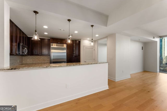 kitchen featuring backsplash, kitchen peninsula, stainless steel appliances, light stone countertops, and light wood-type flooring