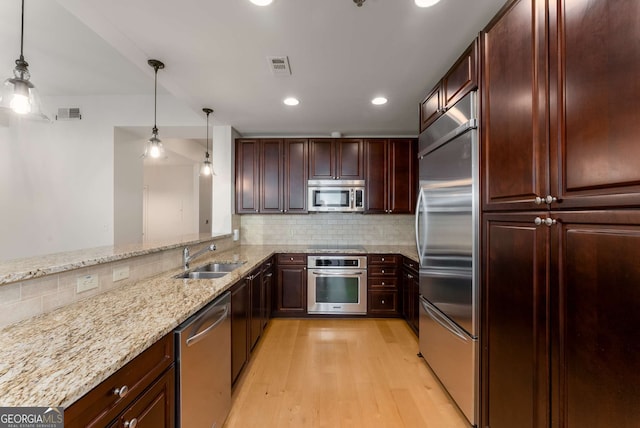 kitchen featuring appliances with stainless steel finishes, sink, hanging light fixtures, and backsplash